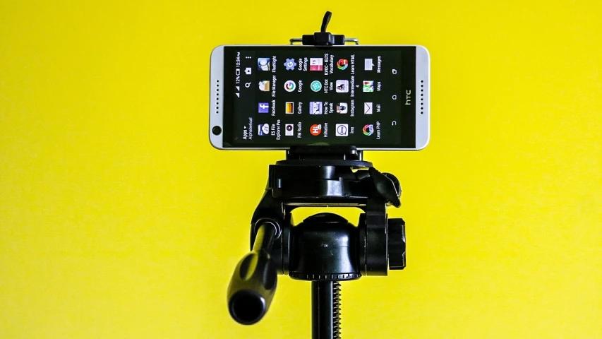 a cell phone sitting on top of a tripod, a portrait, pixabay, video art, on a yellow canva, commercial product photography, upright, cane