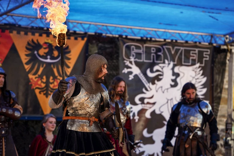 a group of men standing next to each other holding torches, by Grytė Pintukaitė, reddit, hurufiyya, renaissance fair, grey armor, action scene from the film, gryphon