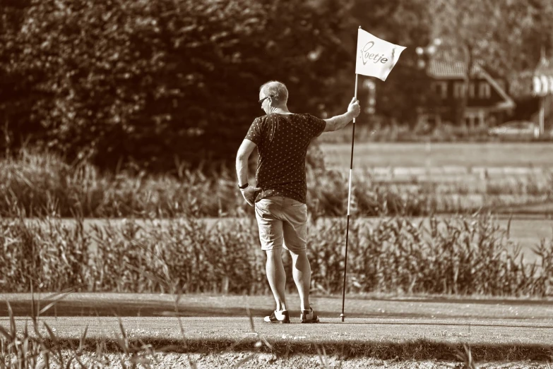 a black and white photo of a man holding a golf flag, a photo, flickr, summer feeling, reportage photo, sepia, are-bure-boke!!!!!!!!