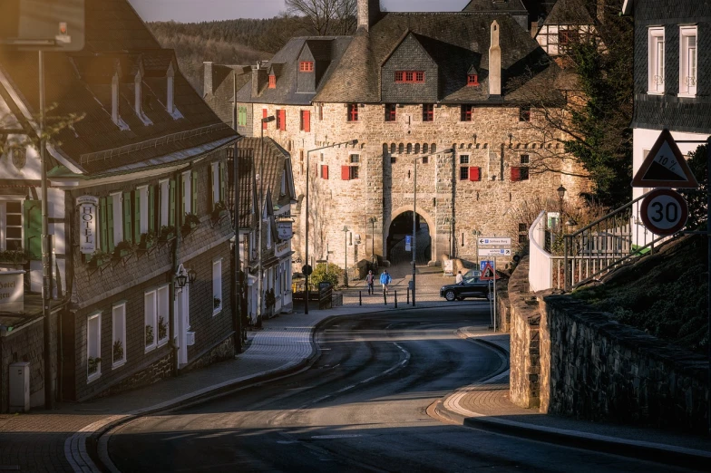 a couple of buildings sitting on the side of a road, by Raphaël Collin, pexels contest winner, romanesque, fortress gateway, bocage, back - lit, busy small town street