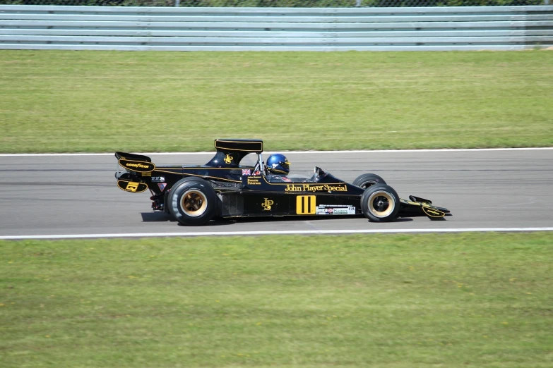 a man driving a race car on a track, a photo, flickr, gold and black color scheme, wikimedia commons, tjalf sparnaay 8 k, 7 0 s photo