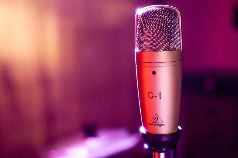 a close up of a microphone on a table, a picture, by Matt Cavotta, shutterstock, gold and purple, coloured gel studio light, cherubic, performing