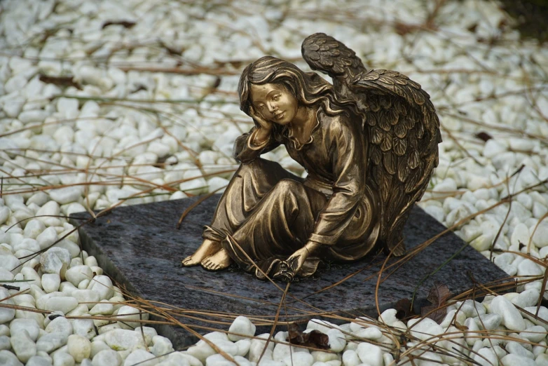 a statue of an angel sitting on a rock, a bronze sculpture, fine art, grieving. intricate, on ground, phone photo, very very well detailed image