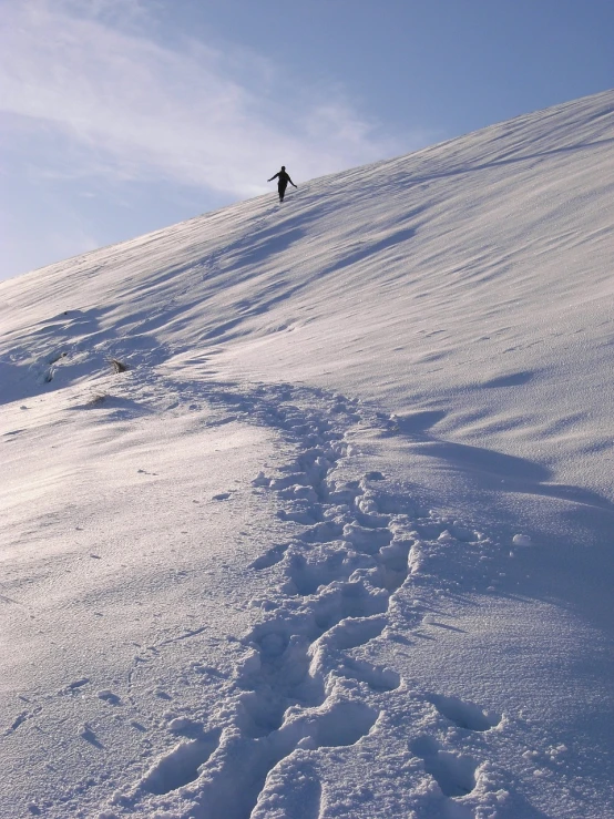 a man riding a snowboard down the side of a snow covered slope, a photo, footprints, wikimedia, man?, trecking