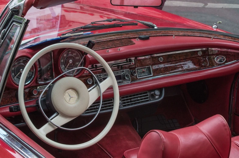 a close up of a car dashboard with a steering wheel, by Etienne Delessert, pexels, retrofuturism, mercedez benz, crimson and white color scheme, convertible, highly ornate