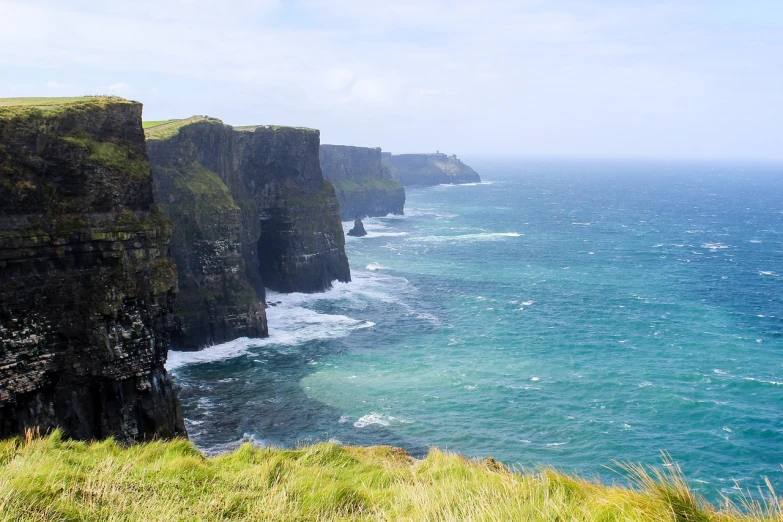 a man standing on top of a cliff next to the ocean, a tilt shift photo, ancient irish, tourist photo, usa-sep 20, the photo shows a large