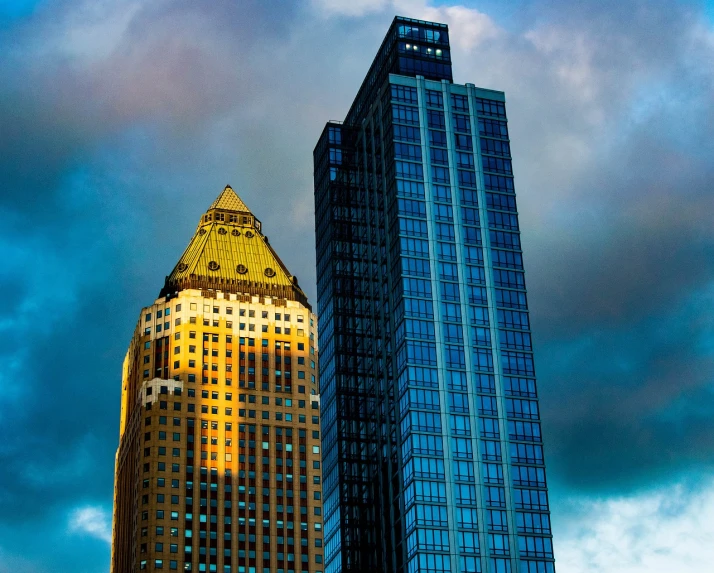 a couple of tall buildings sitting next to each other, a picture, by Andrew Domachowski, pexels contest winner, blue and gold, dramatic contrasting light, pittsburgh, stone and glass and gold