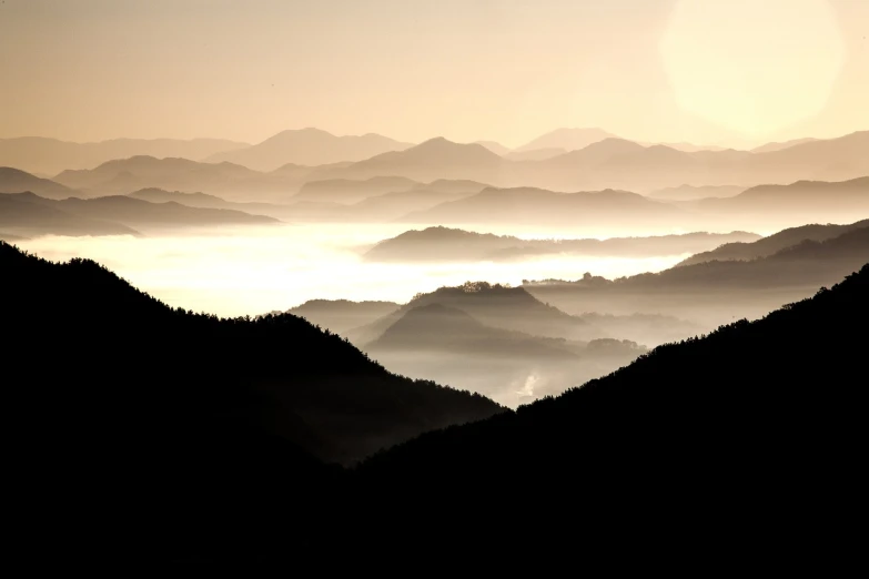 a black and white photo of a mountain range, by Etienne Delessert, flickr, precisionism, mystical orange fog, tuscany hills, japan mountains, overview