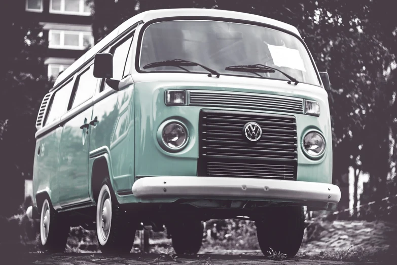 a green van parked in front of a building, a picture, unsplash, fantastic realism, 1970s hippie cloth style, cyan headlights, monochrome, front of car angle