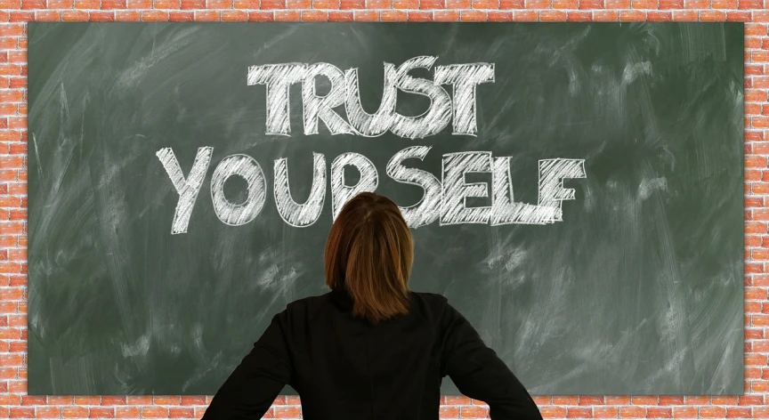 a woman standing in front of a blackboard with trust yourself written on it, a picture, by Kurt Roesch, trending on pixabay, avatar image, seen from below, 😃😀😄☺🙃😉😗, self-confidence