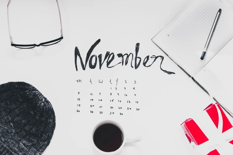 a cup of coffee sitting on top of a desk, a photo, trending on pexels, happening, female calendar, november, black ink on white background, avantgarde 4k wallpaper