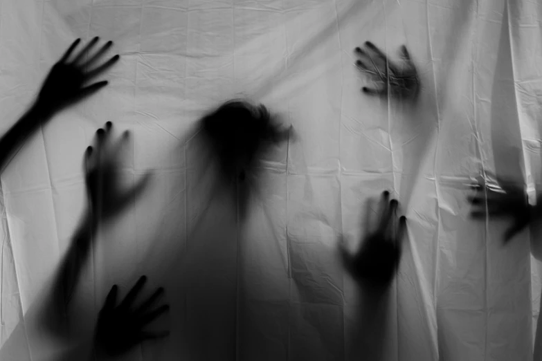 a black and white photo of hands coming out of a sheet, by Gusztáv Kelety, pexels, haunted house themed, human silhouettes, backdrop, sleep paralysis monster