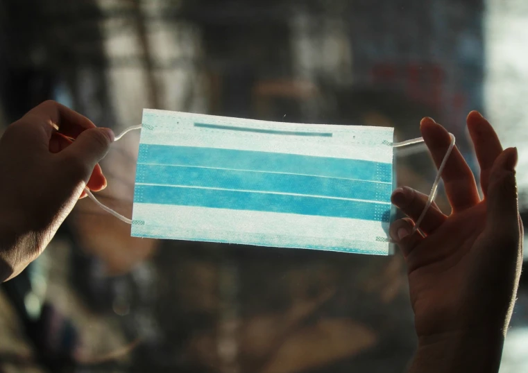 a close up of a person holding a face mask, a picture, transparencies, afp, blue, high quality upload