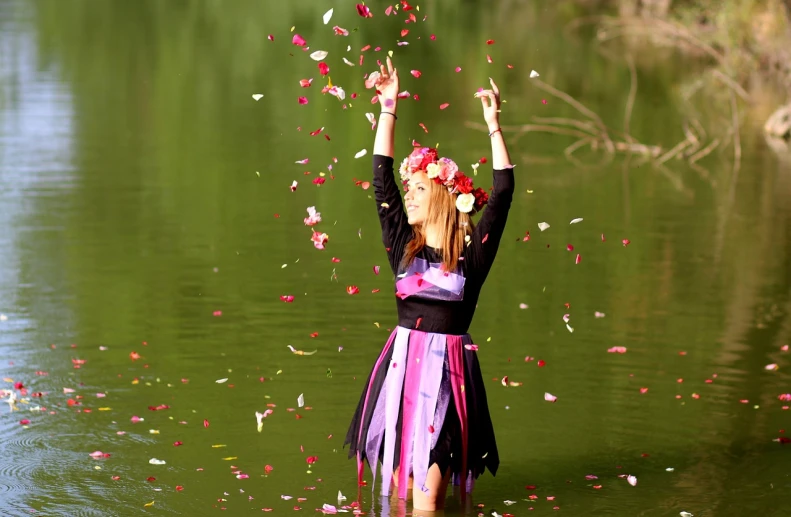 a woman standing in the water throwing petals in the air, ukrainian girl, black and pink dress, beautiful sunny day, in lake