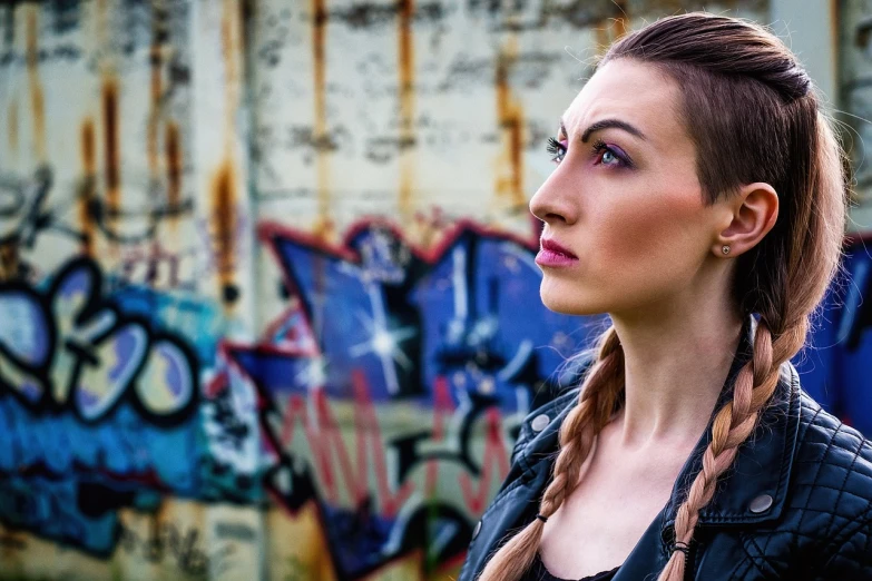 a woman standing in front of a graffiti covered wall, a portrait, by Micha Klein, trending on pixabay, graffiti, pigtails, wearing cyberpunk leather jacket, closeup headshot portrait, portrait sophie mudd