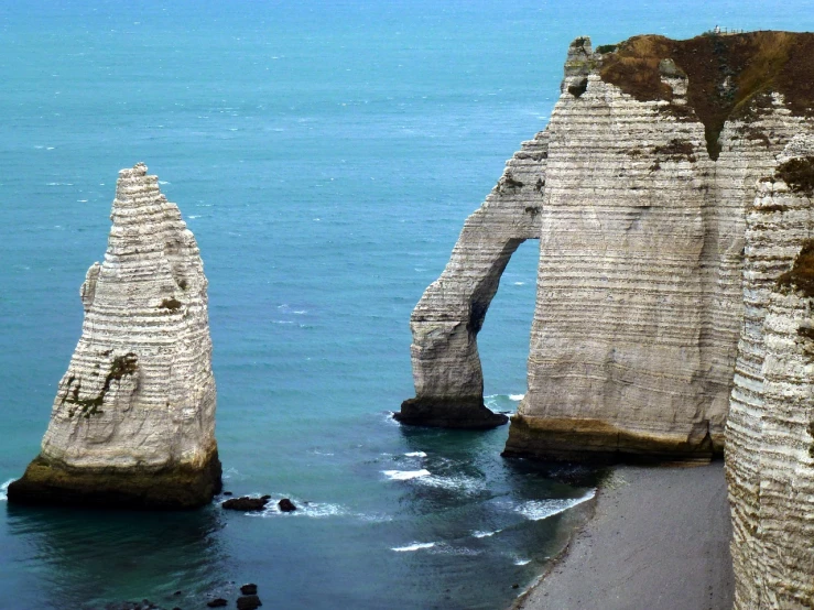 a couple of large rocks sticking out of the water, by François Girardon, massive arch, northern france, telephoto vacation picture, wikipedia