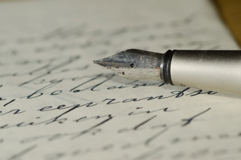 a fountain pen sitting on top of a piece of paper, a macro photograph, letterism, old script, high res photo