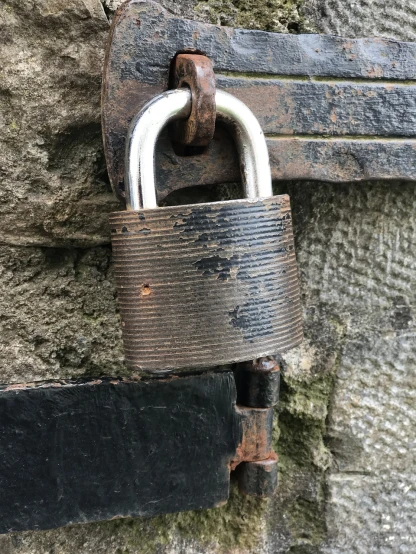 a metal padlock attached to a stone wall, by Richard Carline, scratched photo, maintenance photo, anxious steward of a new castle, shack close up