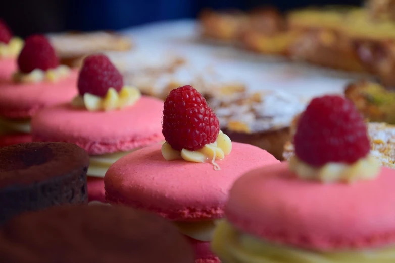 a close up of a tray of pastries with raspberries on top, romanticism, macaron, vibrant colour, 7 0 mm photo