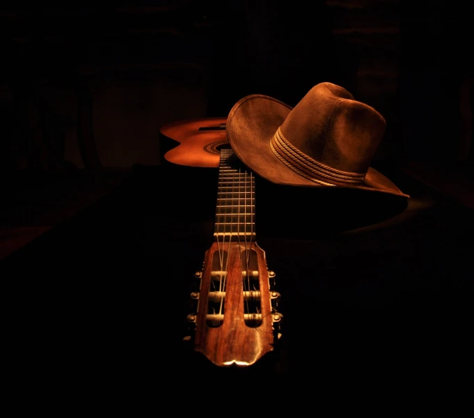 a hat sitting on top of an acoustic guitar, inspired by James Bard, photo taken at night, wild west theme, photo taken in 2018, chiaroscuro!!