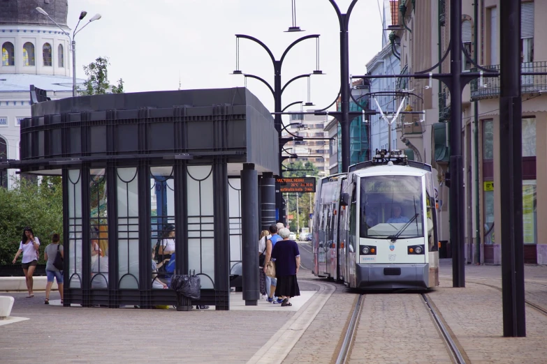 a train stopped at a bus stop on a city street, a picture, by Mathias Kollros, shutterstock, paris 2010, budapest, 1998 photo, underground facility