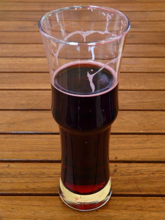 a glass of wine sitting on top of a wooden table, by John Henderson, inside a beer glass, berry juice, 2 0 1 4, blending