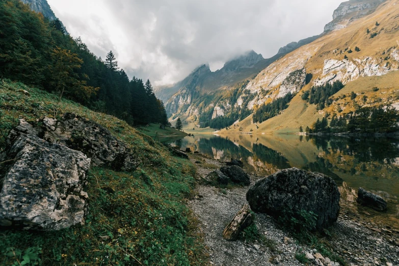 a body of water sitting on top of a lush green hillside, a picture, by Johannes Voss, pexels, les nabis, autumn mountains, overcast lake, time to climb the mountain path, incredible wide screenshot