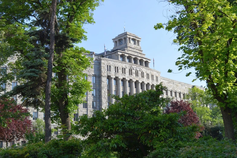 a large building with a clock on top of it, by Arthur Sarkissian, flickr, vancouver school, built into trees and stone, the city is full of green plants, gwanghwamun, neoclassical style