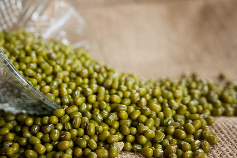 a glass bowl filled with green peas on top of a table, by Maksimilijan Vanka, pexels, visual art, picking up a can beans, mineral grains, side view close up of a gaunt, linen