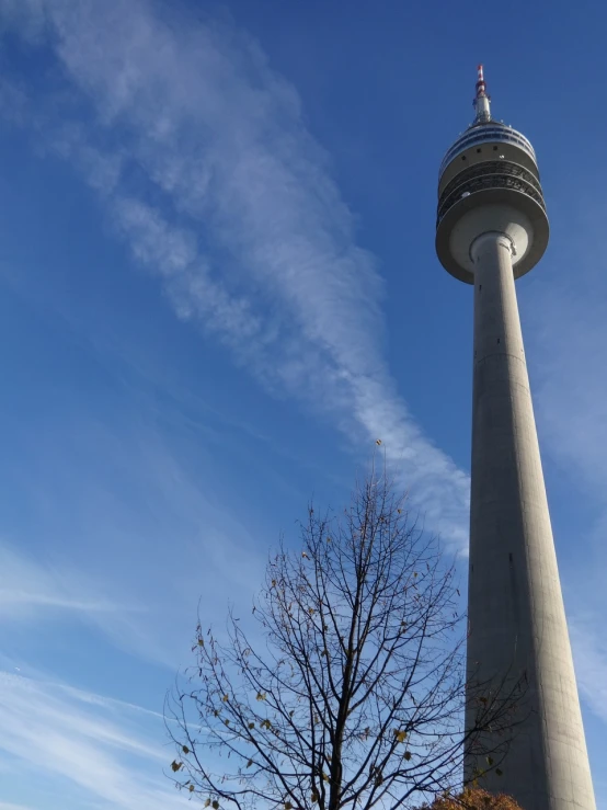 a tall tower with a clock on top of it, a picture, by Jens Søndergaard, contrails, berlin park, stratosphere, family friendly