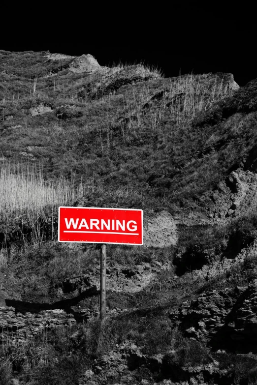 a red warning sign sitting on the side of a hill, a photo, happening, bw photo, rendering, document photo, dark photo