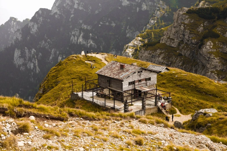 a building sitting on top of a lush green hillside, by Jozef Simmler, shutterstock, interior of a mountain hut, detailed wide shot, pub, makeshift house
