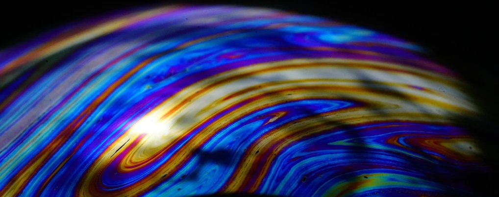 a close up of a colorful object on a black background, a microscopic photo, by Doug Ohlson, lyrical abstraction, refracted sunset, abstract rippling background, thin blue arteries, taken on a 2010s camera