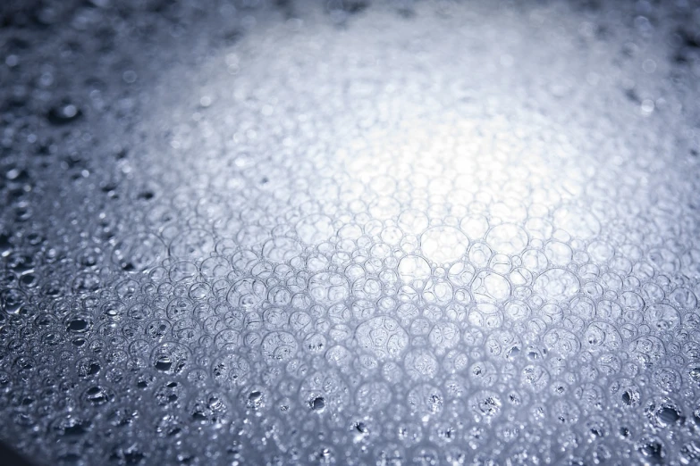 a close up of water droplets on a surface, a microscopic photo, icy cold pale silent atmosphere, small finely stippled light, lots of bubbles, sun lit