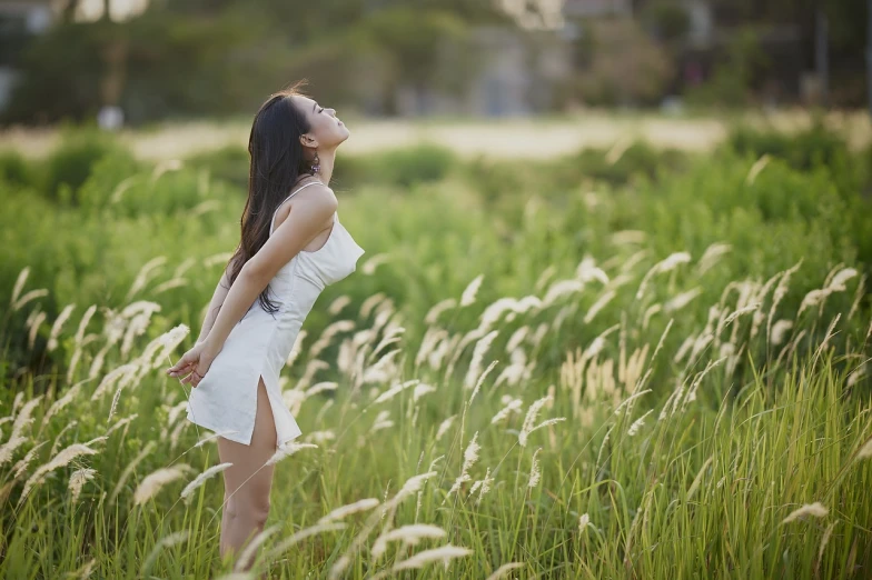 a woman standing in a field of tall grass, a picture, by Li Mei-shu, shutterstock, fine art, wearing white camisole, beautiful young korean woman, zen feeling, 7 0 mm photo