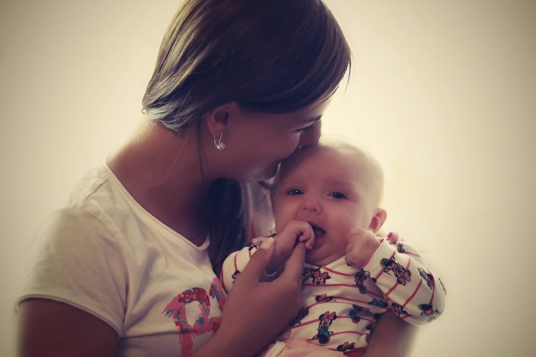 a woman holding a baby in her arms, a picture, tumblr, romanticism, portrait mode photo, enhanced photo, licking, closeup photo
