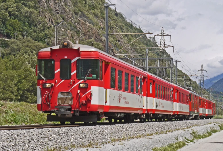 a red and white train traveling down train tracks, by Karl Völker, tarski fiume, accompanying hybrid, alps, goto fujita