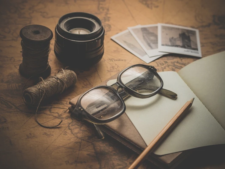 a pair of glasses sitting on top of an open book, a picture, art photography, 40's adventurer, drawing pictures on a notebook, retro atmosphere, adventuring