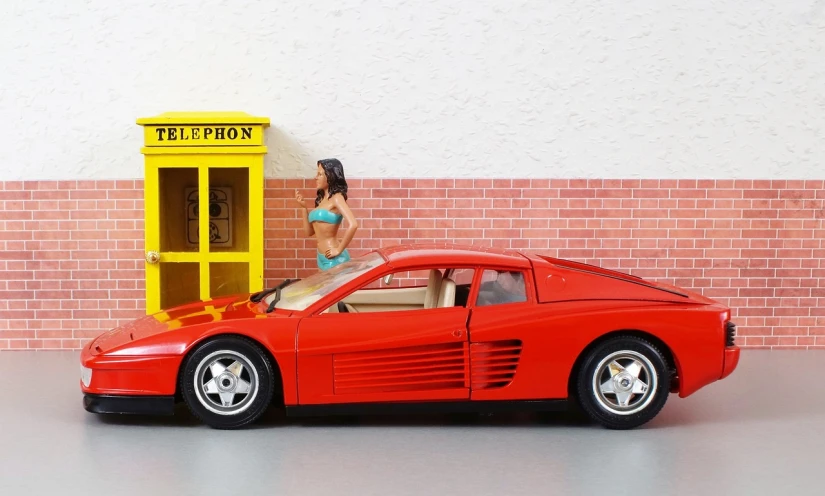 a red toy car parked in front of a phone booth, inspired by Bernardo Cavallino, photorealism, woman model, saleen s7, barbie, in front of a garage