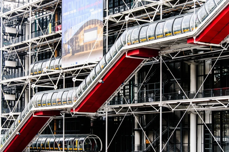 a train that is sitting in front of a building, by Raphaël Collin, flickr, paris school, red trusses, elegant walkways between towers, with big chrome tubes, stairway to heaven