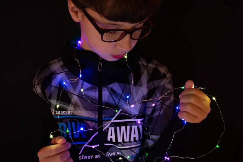 a young boy holding a string of christmas lights, inspired by Jean Malouel, ultraviolet and neon colors, with glasses, product introduction photos, packshot