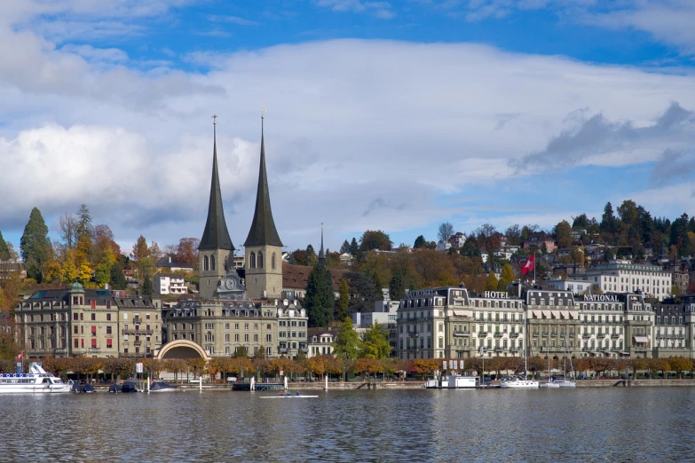 a large body of water with a bunch of buildings in the background, by Emanuel Büchel, shutterstock, lead - covered spire, swiss architecture, wide long view, viewed from the harbor