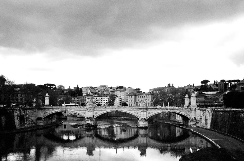 a black and white photo of a bridge over a river, by Mirabello Cavalori, rome in background, overcast!!!, reflects, ancient rome