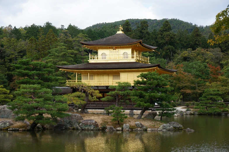 a building in the middle of a body of water, inspired by Shūbun Tenshō, flickr, full of golden layers, yellow carpeted, with matsu pine trees, 7 0 mm photo