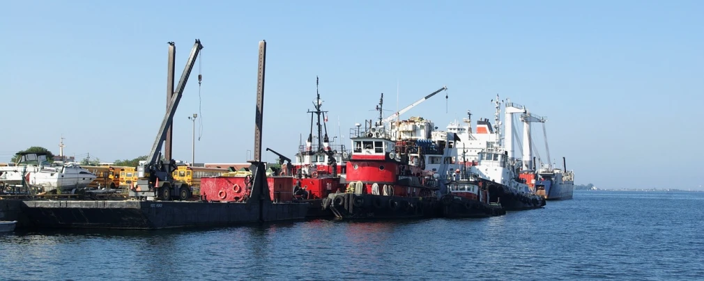 a couple of boats that are sitting in the water, shipping docks, it has a red and black paint, viewed from the harbor, group photo