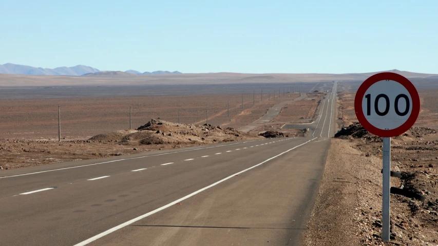 a red and white sign sitting on the side of a road, by Dennis Ashbaugh, flickr, les nabis, chile, panorama distant view, sahara, black road