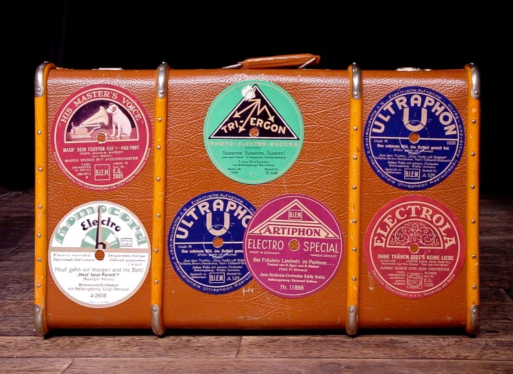 a brown suitcase sitting on top of a wooden floor, by Wayne England, flickr, beautiful labels, vinyl records, various posed, rack