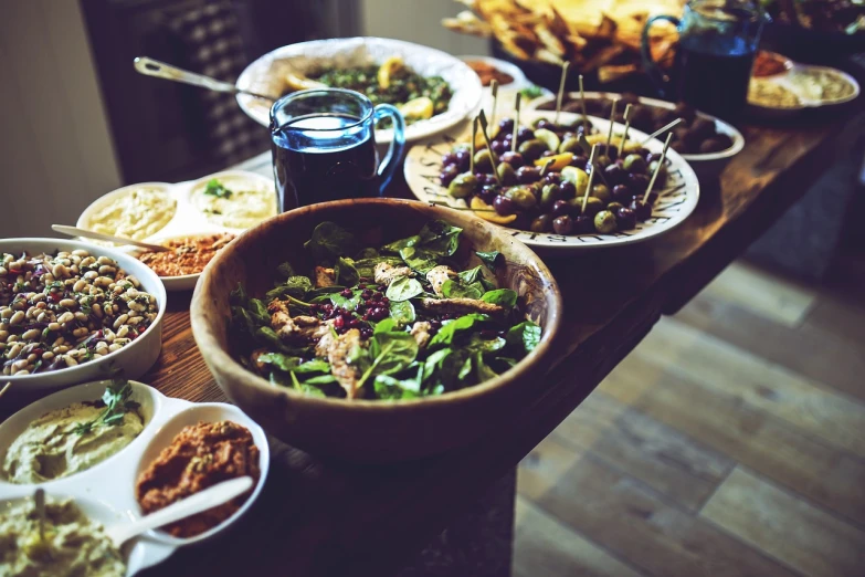 a wooden table topped with plates of food, shutterstock, retro effect, salad, olives, stock photo