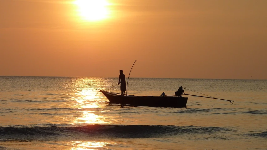 a man standing on top of a boat in the ocean, a picture, by Scott M. Fischer, fishing boat, sunset on the beach, wikimedia, cambodia