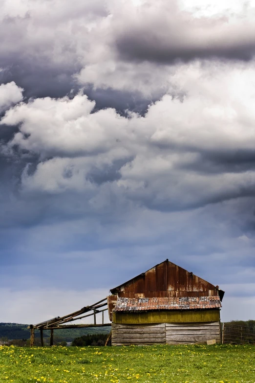 a barn sitting on top of a lush green field, a portrait, baroque, dramatic stormy sky, tarnished and rusted metal, an australian summer landscape, roof background